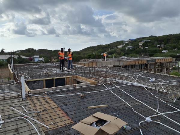 Workers on a rooftop slab with electrical conduit rough-in
